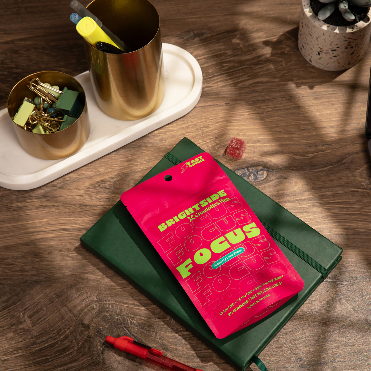 Pink 'Brightside' focus supplement package on a green notebook with office supplies on a wooden surface.