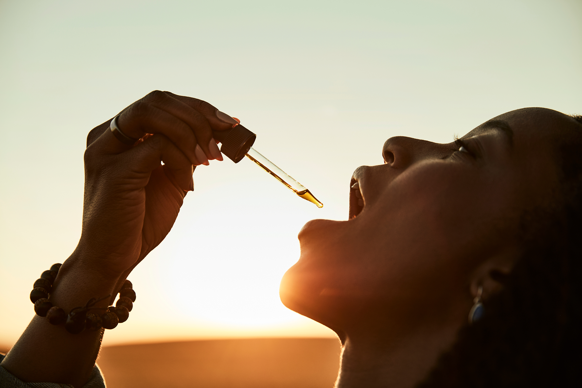 Person using a dropper with a sunset in the background