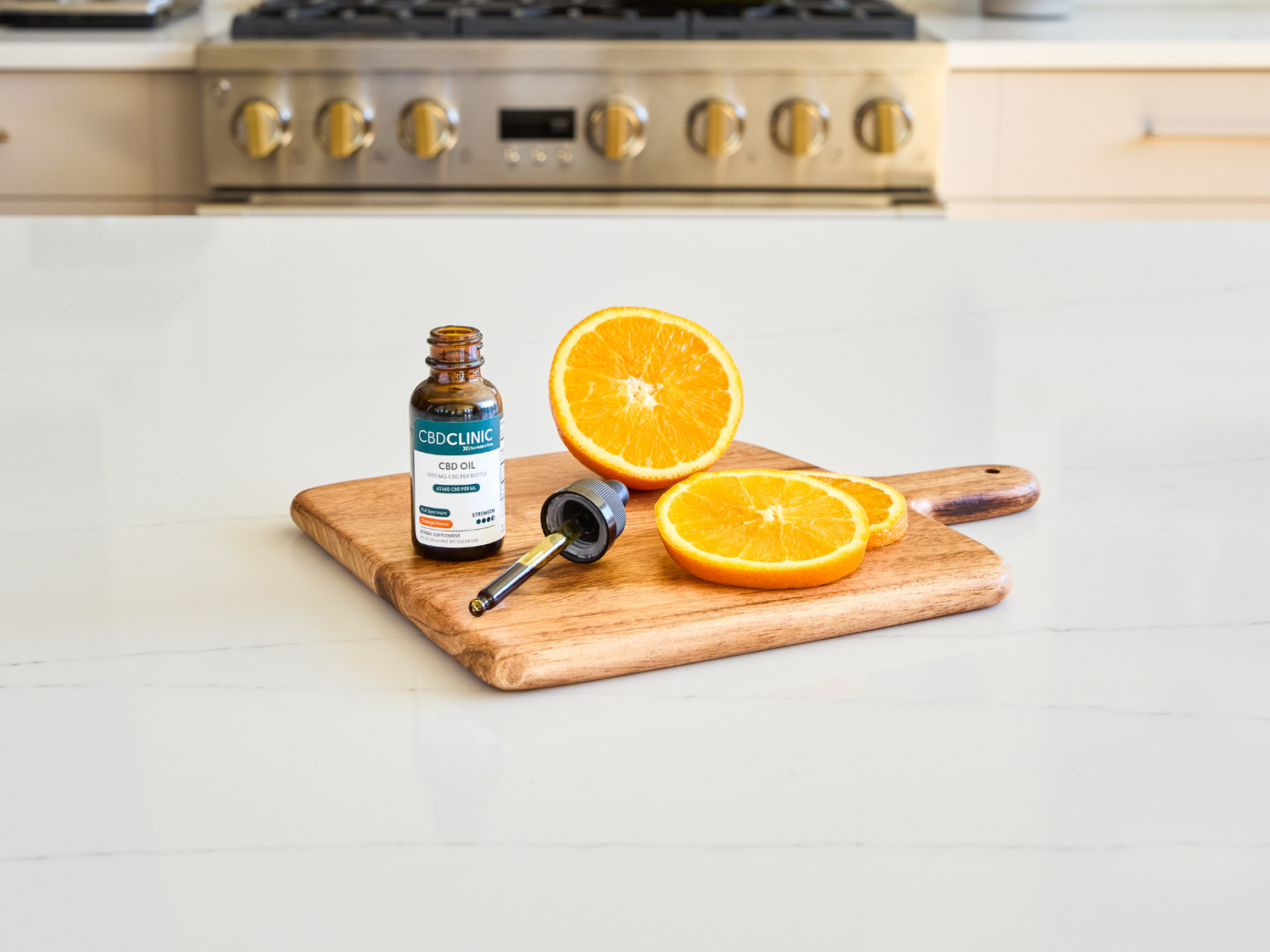 Orange halves and a bottle on a cutting board with a kitchen stove in the background