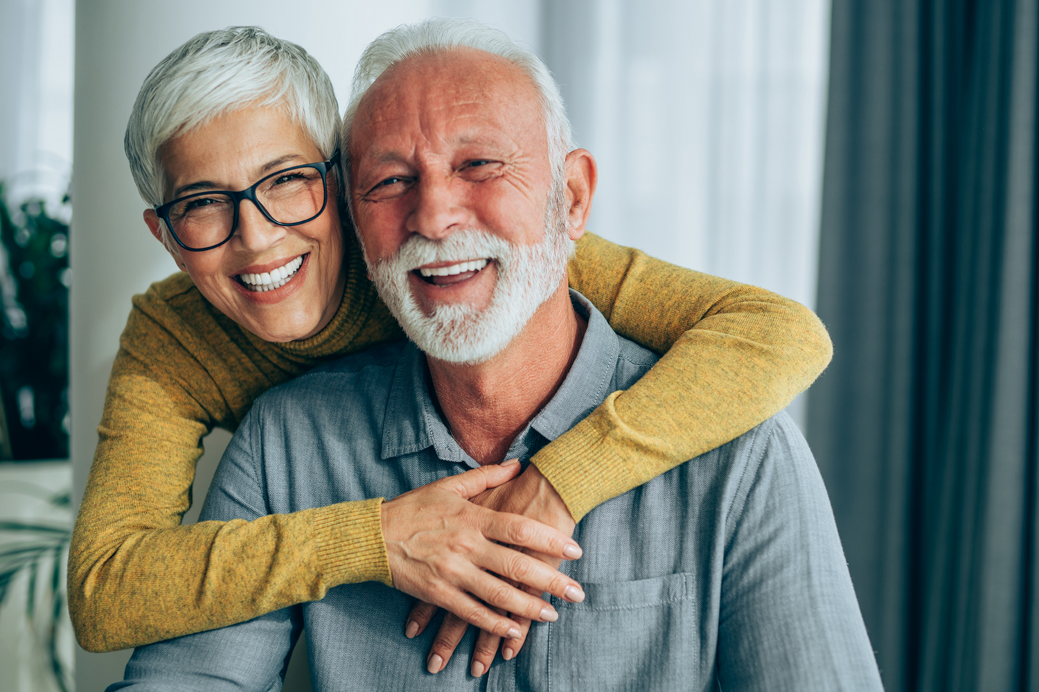 Happy elderly couple embracing indoors with a blurred background