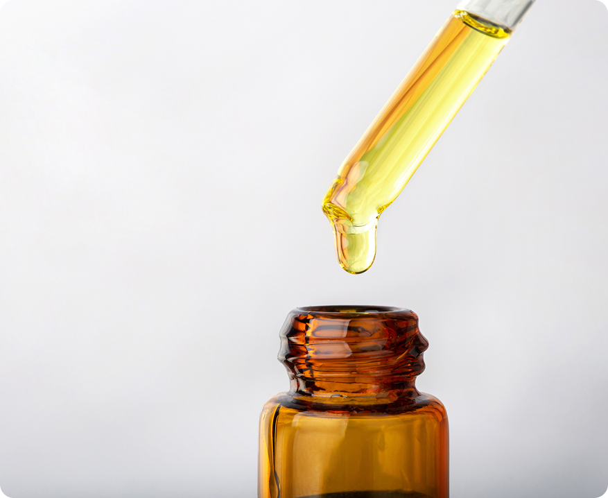 Amber glass dropper bottle with yellow liquid being dispensed on a white background