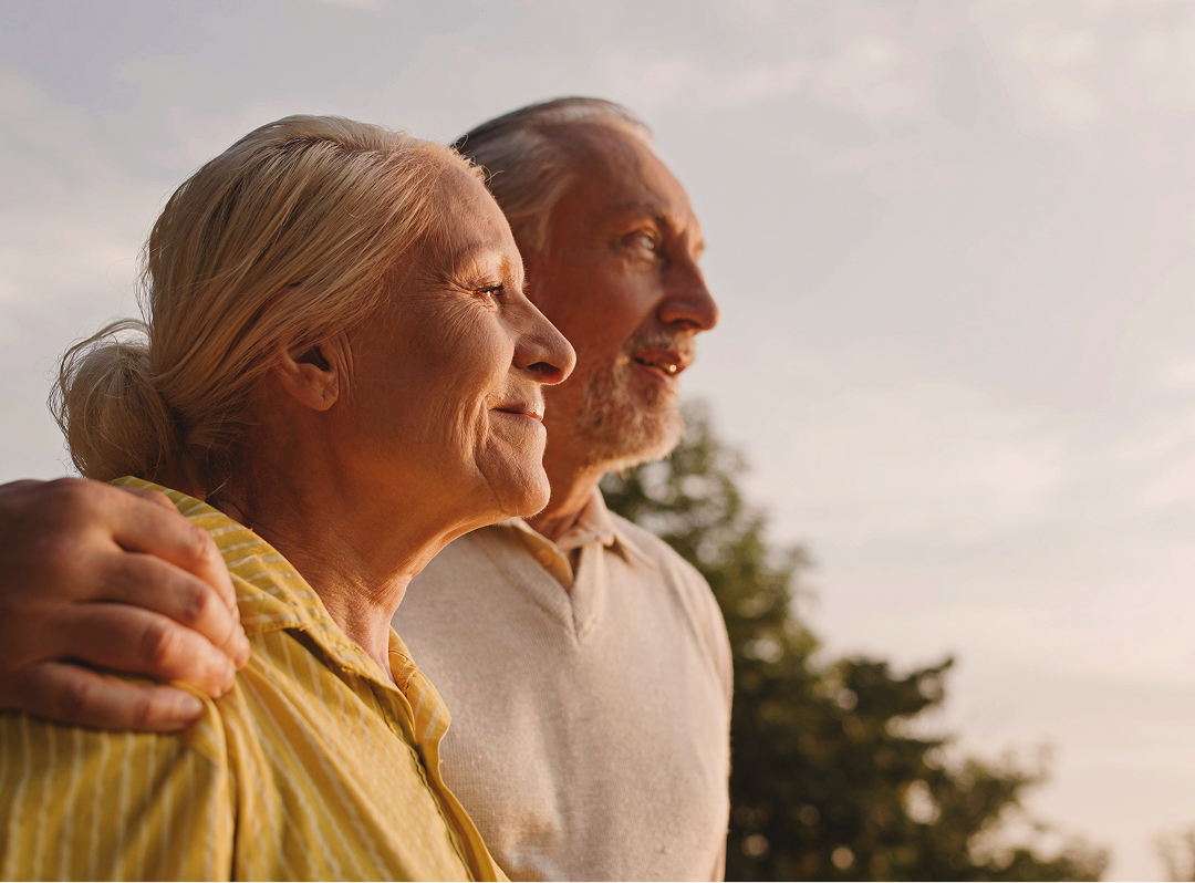 Man with arm around woman outside looking into the distance